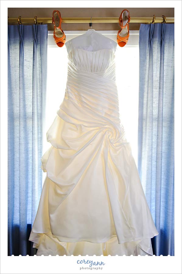 bride's wedding dress hanging up with shoes