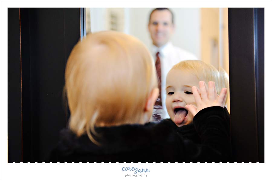 one year old sticking tongue out at herself in a mirror