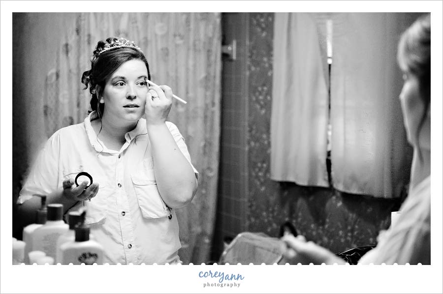 bride putting on makeup in the mirror