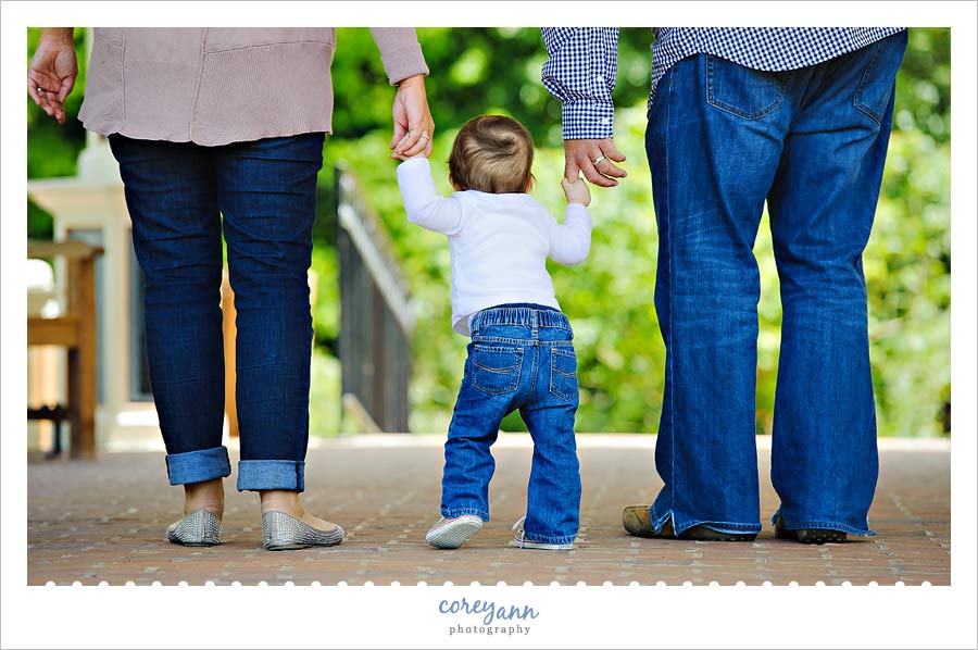 Family Portrait Session at Fellows Riverside Gardens one year old child walking with parents at fellows riverside gardens