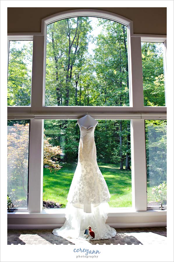 wedding dress hanging in window with shoes