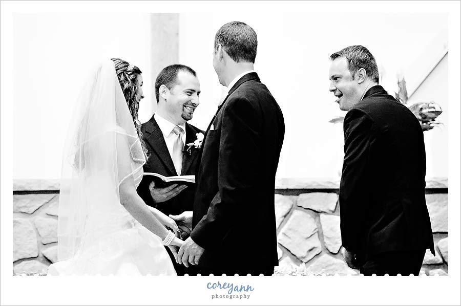 best man laughing as he hands rings to pastor during wedding ceremony
