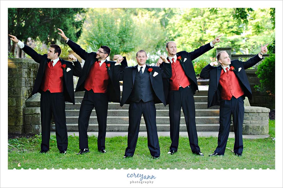 groomsman in black tuxes with red vests posing with groom in ohio