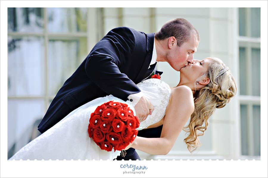 groom dipping bride with red rose bouquet in Ohio