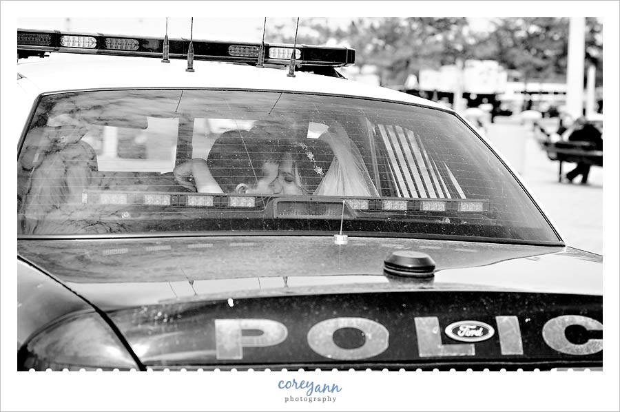 bride and groom in the back of a police cruiser