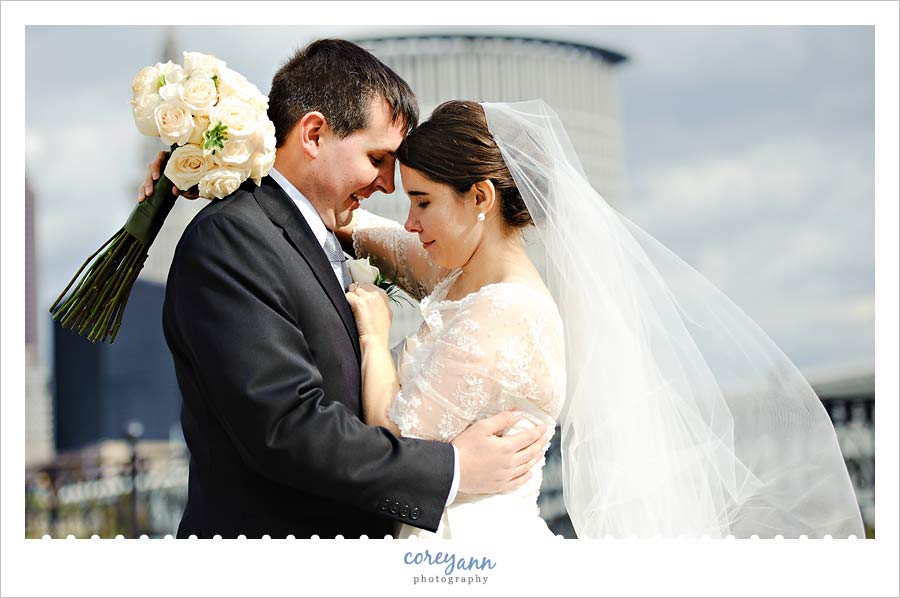 bride and groom with cleveland skyline in downtown cleveland