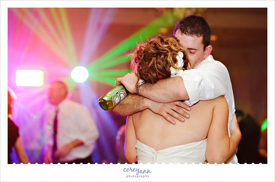bride and groom kiss on dance floor with DJ lights