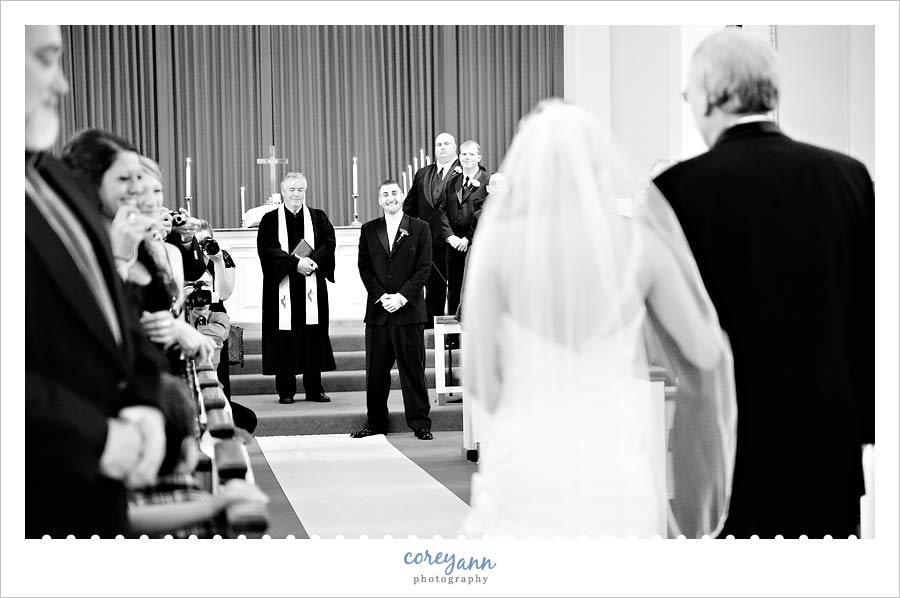 bride and father walking down aisle toward groom