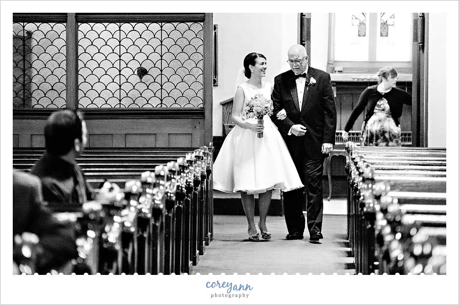 bride and father walking up the aisle to wedding ceremony at old stone church