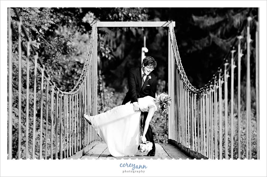 groom dipping bride on suspension bridge at kirtland country club